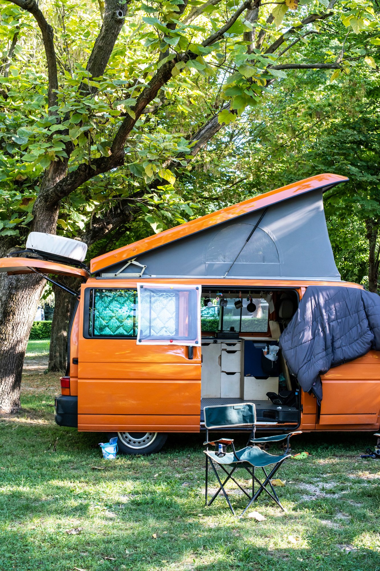 Camper in campsite. Outdoor equipment and travel van on green me Camper in campsite. Outdoor equipment and travel van on green me