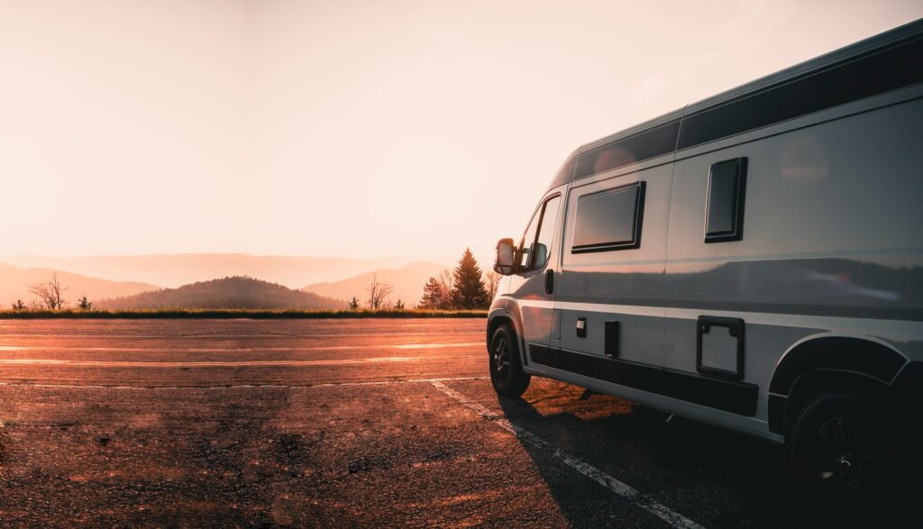 Campervan parked on the side of the road against a scenic sunset
