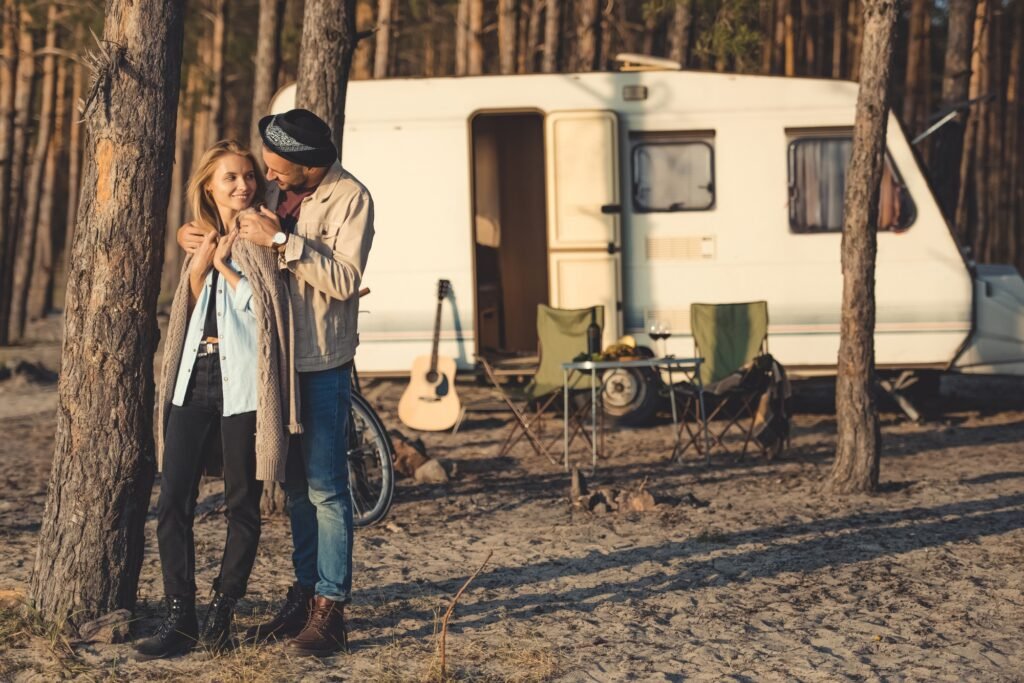 handsome boyfriend hugging girlfriend near campervan in forest