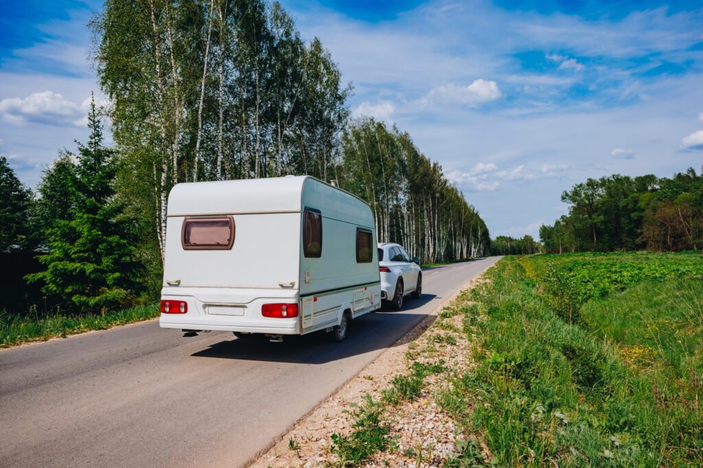White caravan driving road on the way to the vacations. Beautiful camping holidays with camping car